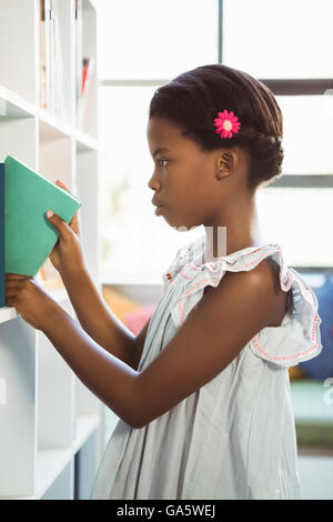 Girl taking a book from bookshelf in library Stock Photo - Alamy
