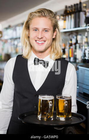 Portrait of waiter holding tray with beer mug Stock Photo