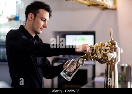 Bartender pouring beer in glass from faucet Stock Photo