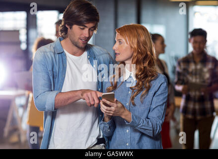 Colleagues discussing while using mobile phone in office Stock Photo