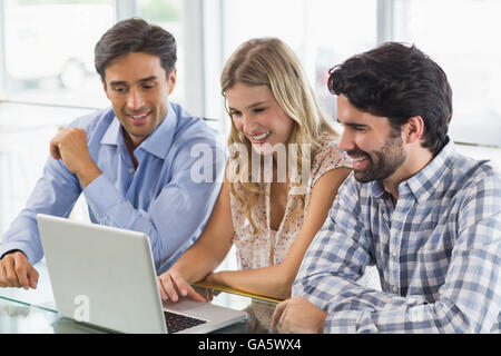 Smiling woman and two men using laptop Stock Photo