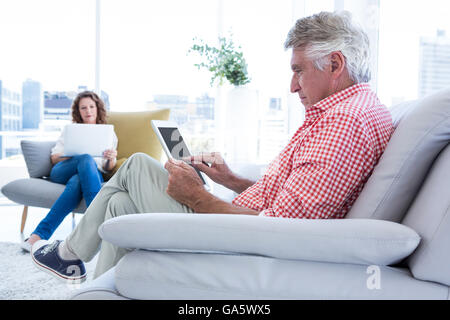 Mature man using tablet computer while sitting Stock Photo