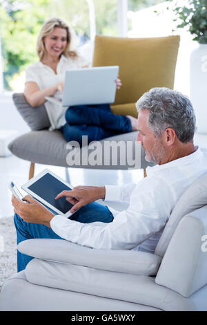 Mature man using tablet while woman holding laptop Stock Photo