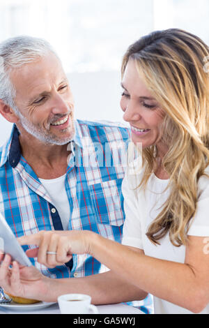 Woman pointing on digital tablet while sitting by husband Stock Photo