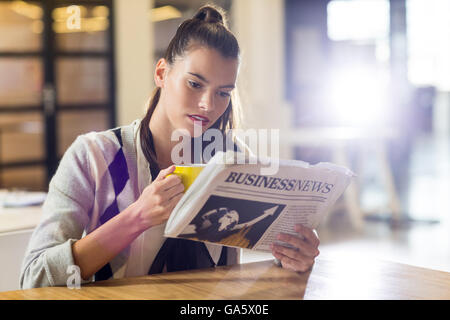 Woman reading newspaper in office Stock Photo