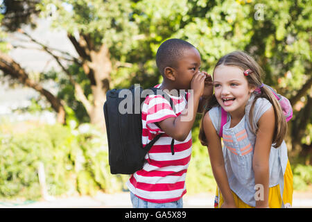 Boy whispering a secret in girls ear Stock Photo