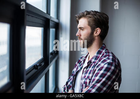 Thoughtful man standing by window Stock Photo