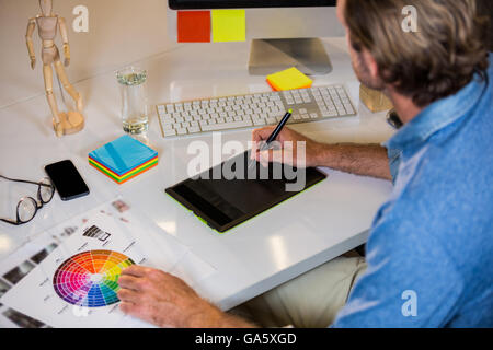 Businessman using graphics tablet at desk Stock Photo