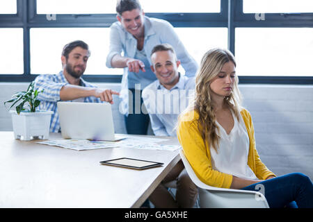 Colleagues laughing on businesswoman in office Stock Photo