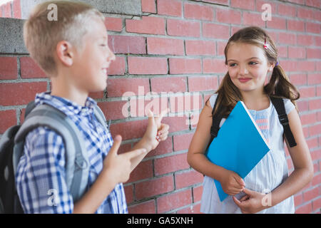 Schoolkids talking to each other in corridor Stock Photo