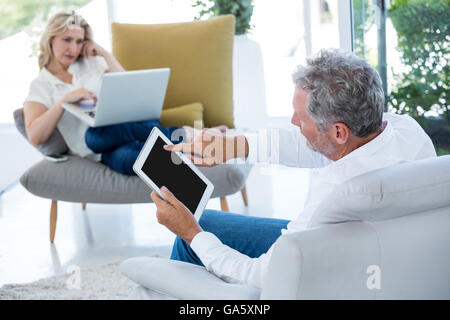 Man using tablet while woman holding laptop Stock Photo