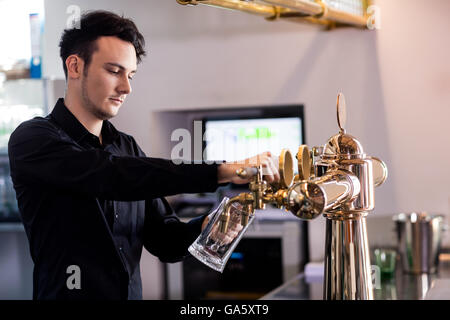 Barkeeper pouring beer in glass at counter Stock Photo