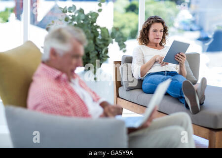 Woman using digital tablet while relaxing on seat Stock Photo