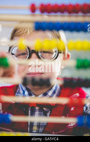 Close-up of schoolkid looking through abacus in classroom Stock Photo