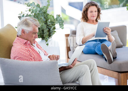 Mature couple using laptop and digital tablet Stock Photo