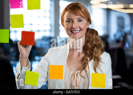 Portrait of businesswoman writing on adhesive notes Stock Photo