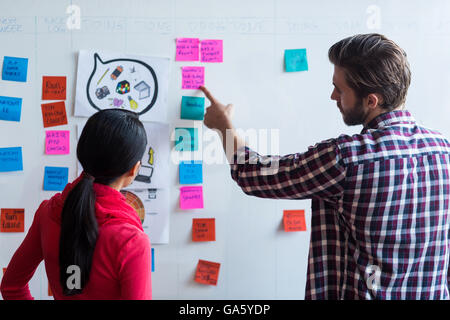 Colleagues discussing about sticky notes in office Stock Photo