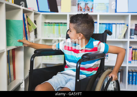 Disabled boy selecting a book from bookshelf in library Stock Photo