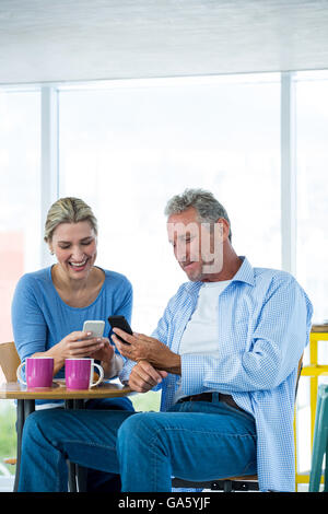 Couple using mobile phone at cafe Stock Photo