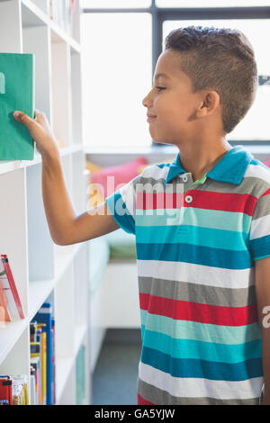 Boy taking a book from bookshelf in library Stock Photo