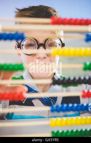 Close-up of schoolkid looking through abacus in classroom Stock Photo
