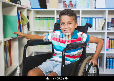 Disabled boy selecting a book from bookshelf in library Stock Photo