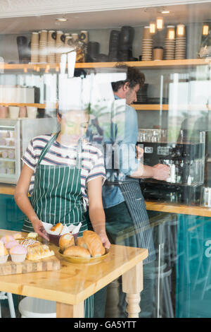 Waitress arranging dessert and snack on the counter while waiter preparing coffee Stock Photo