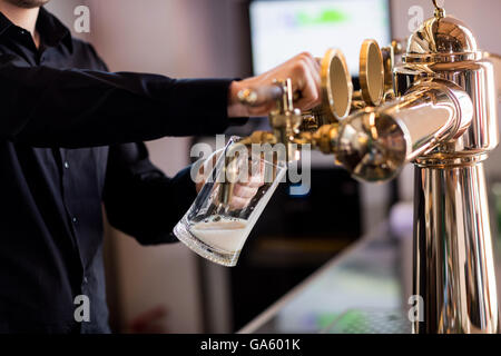 Bartender pouring beer from faucet in pint glass Stock Photo