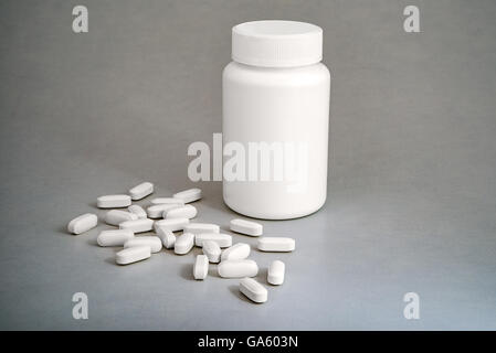 White plastic medicine bottle with white pills on gray background Stock Photo