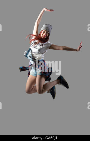 Portrait of attractive smiling fit cute hipster casual young woman wearing beanie dancing and jumping with happy face Stock Photo