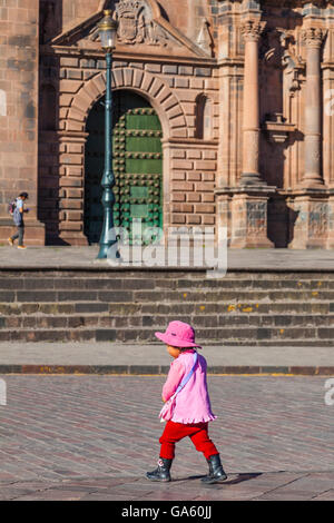 Young Peruvian child walking across the road in the Plaza de Armas, Cusco, Peru Stock Photo