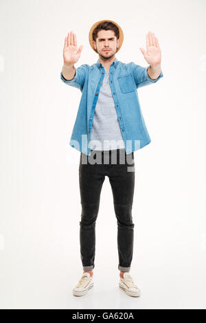 Full length of angry young man standing and showing stop gesture over white background Stock Photo