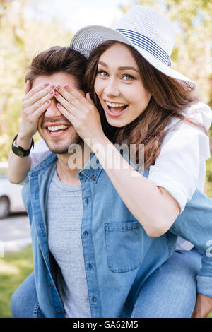 Portrait of a handsome young man carrying his girlfriend on his back outdoors in the park Stock Photo
