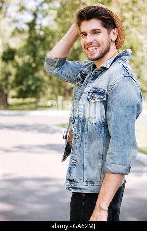 Close-up portrait of a handsome hipster guy holding camera wearing hat outdoors in the park Stock Photo