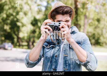 Happy casual hipster man making photo using camera outdoors Stock Photo