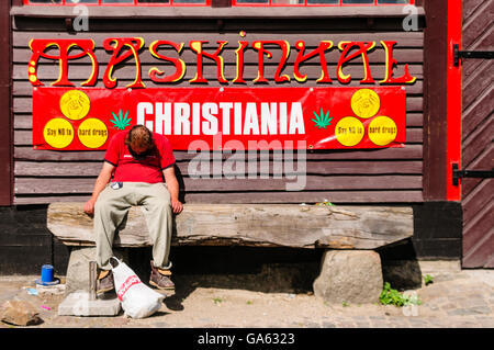 A man sits sleeping in front of a sign saying 'Say NO to hard drugs' in Freetown Christiana, Copenhagen Stock Photo