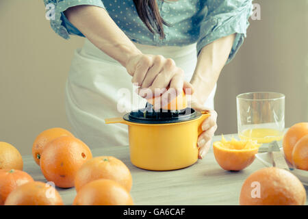 Woman squeezing oranges on a table, preparing juice, flat closed Stock Photo