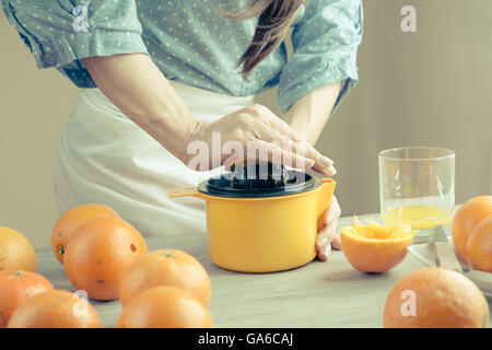 Woman squeezing oranges on a table, preparing juice, flat closed Stock Photo