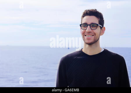Portrait of young latin man by the ocean. Hispanic man smiling. Stock Photo