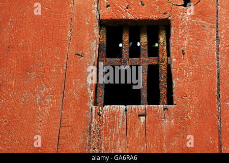 Window with old rusted and broken iron bars in orange colored door Stock Photo
