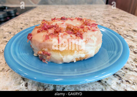 Bacon and Maple Donut on blue dessert plate with granite countertop background closeup macro Stock Photo