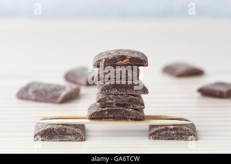 Dark cooking chocolate pieces arranged on wooden toothpicks with copy space Stock Photo