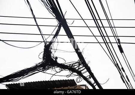 Many wires messy with power line cables, transformers and phone lines on old electricity pillar or Utility pole at beside road a Stock Photo