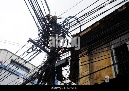 Many wires messy with power line cables, transformers and phone lines on old electricity pillar or Utility pole at beside road a Stock Photo