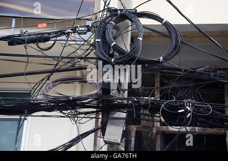 Many wires messy with power line cables, transformers and phone lines on old electricity pillar or Utility pole at beside road a Stock Photo