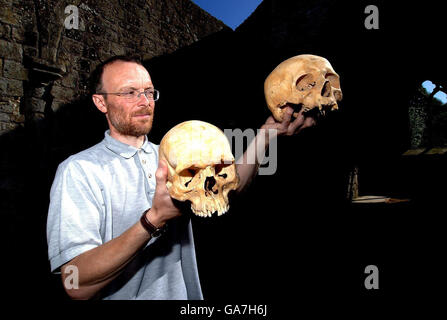 Simon Mays, the English Heritage Skeletal Biologist stands in the ruins of Wharram Percy a deserted village, with a 13th Century skull (left) and a 11th Century skull found in the village, the skulls have revealed a puzzling shift in skull shapes of humans between those centuries. Stock Photo