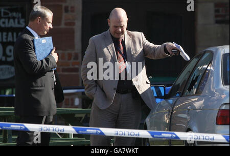 A police officer points at the broken window of a car, outside the Fir tree pub in Croxteth, Liverpool, which is believed to have been hit by a stray bullet in the attack which killed 11-year-old Rhys Jones last night. Stock Photo