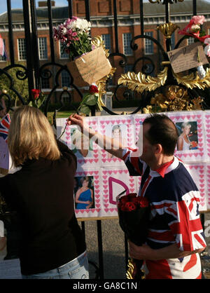 Mourners place roses above a poster in the gates outside Kensington Palace - the former home of Diana, Princess of Wales - ahead of today's Service of Thanksgiving. Stock Photo