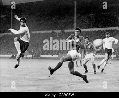 England's Geoff Hurst (l) smashes the ball past Northern Ireland's Terry Neil (c) to score the opening goal, watched by teammate Martin Peters (r) Stock Photo