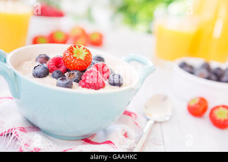 A bowl with homemade oatmeal porridge with fresh fruit on a rustic outdoor table. Stock Photo